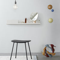 Black stool against a light grey wall, featuring colorful decor accents in earth tones and deep blue. 