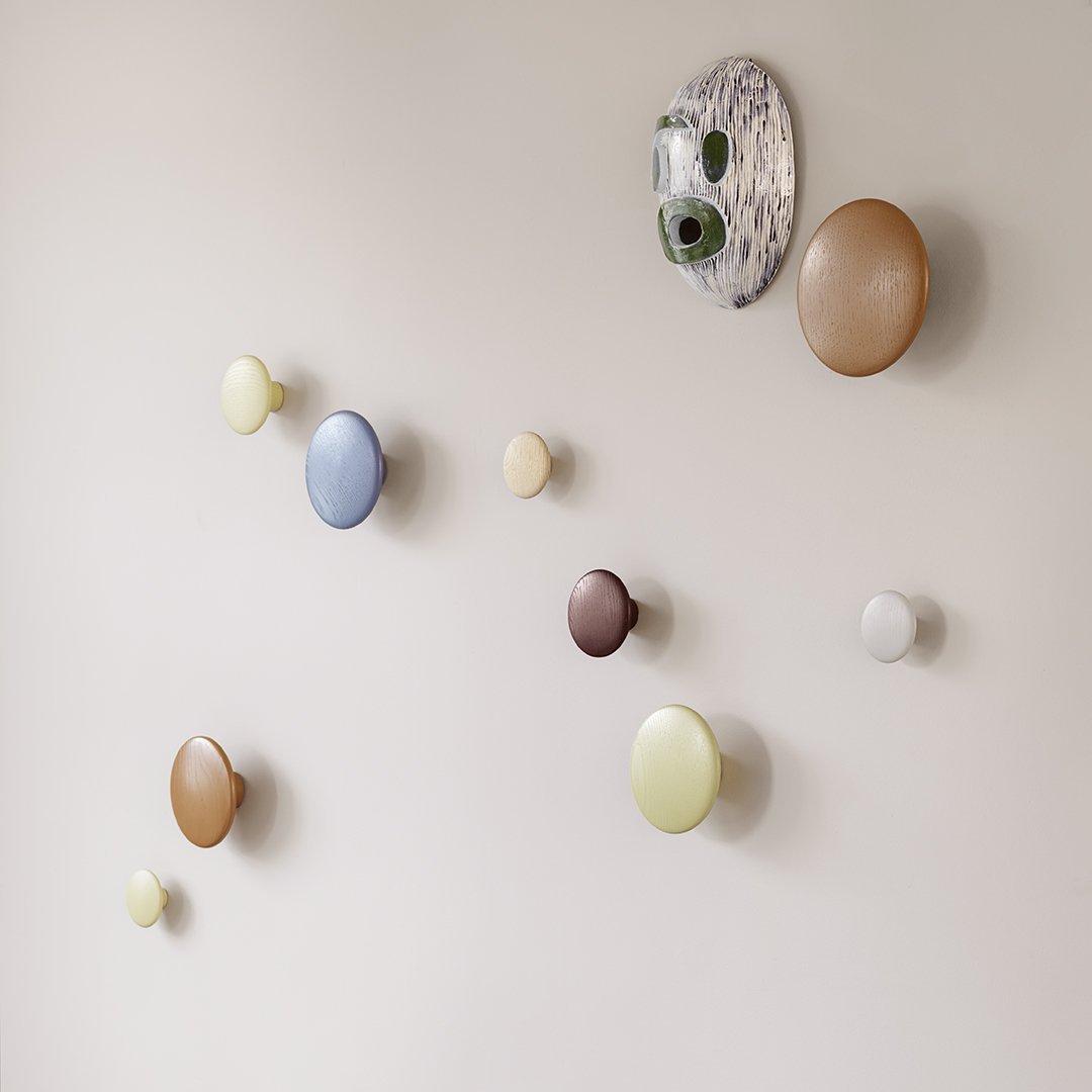 Colorful, round wall hooks in shades of blue, yellow, brown, and white with a unique patterned backdrop. Perfectly styled decor.