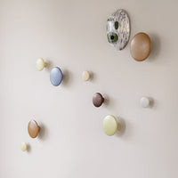 Colorful, round wall hooks in shades of blue, yellow, brown, and white with a unique patterned backdrop. Perfectly styled decor.