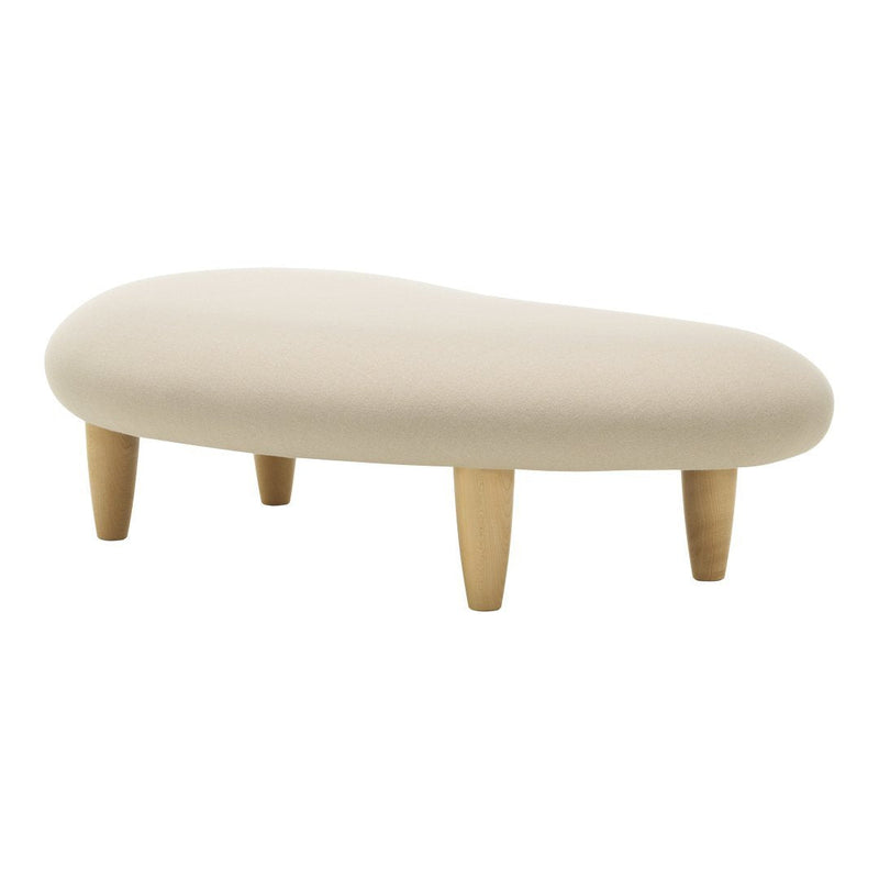 Beige organic-shaped ottoman with natural wooden legs, featuring a soft textured fabric.