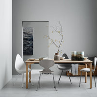 Neutral gray walls with a light wooden table, white and gray chairs, and subtle organic decor accents.
