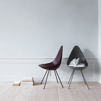 Modern chairs in deep burgundy and sleek black, featuring minimalist designs on a light wooden floor.