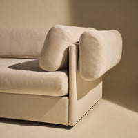 Beige modern sofa with unique curved armrests, featuring a minimalist design and soft, velvety texture.