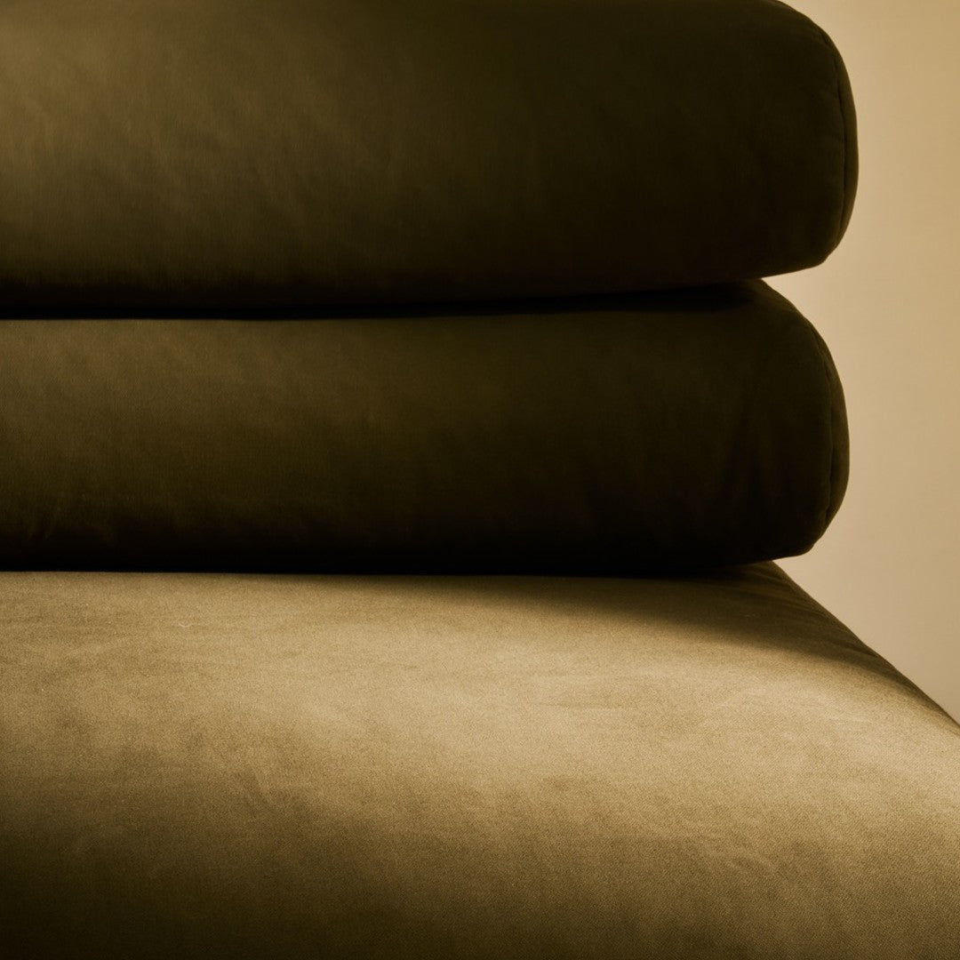 Dark green layered cushions with a smooth, velvety texture against a soft beige background.
