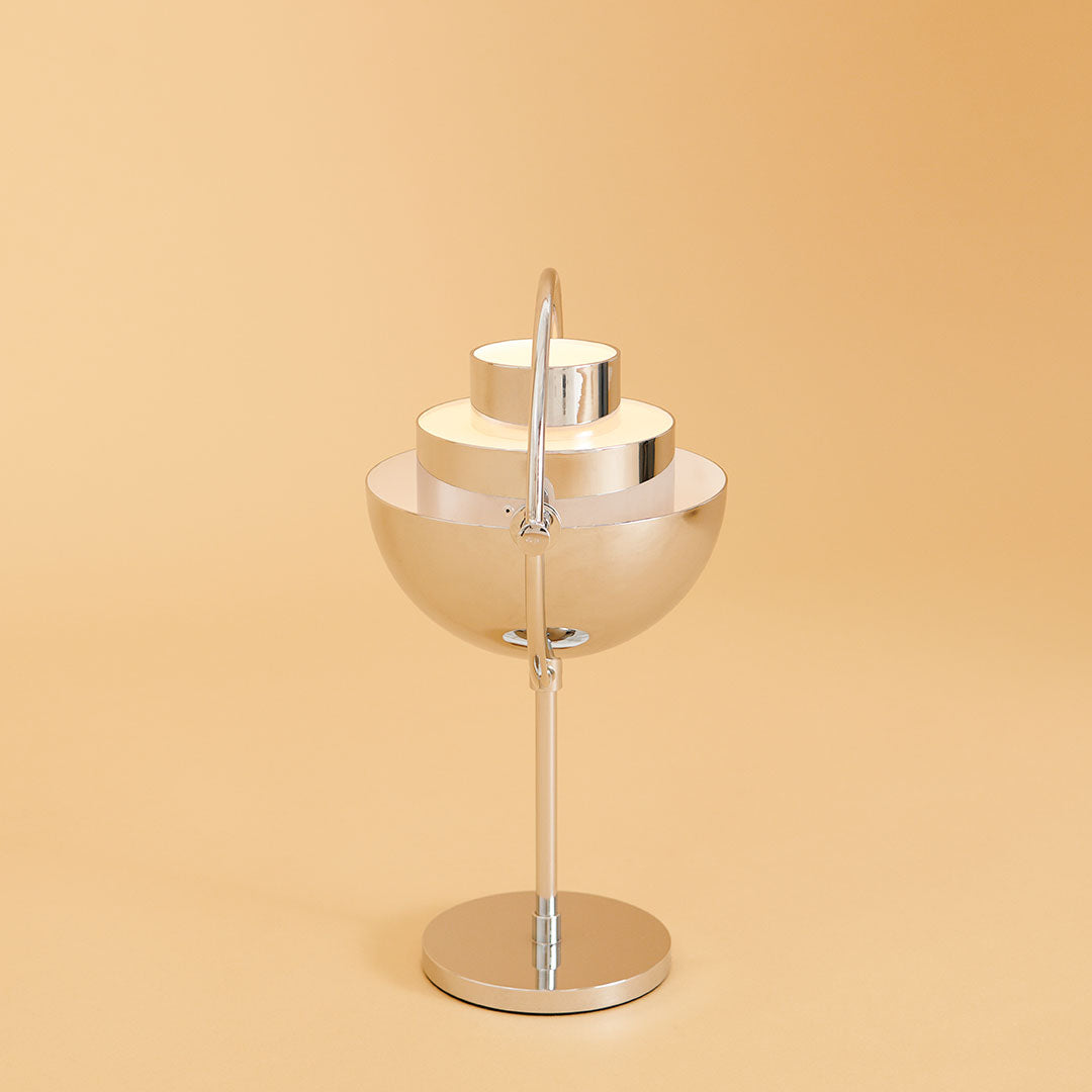 Modern silver lamp with layered metallic shades, set against a warm beige background. Stylish and minimalist design.