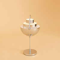 Modern silver lamp with layered metallic shades, set against a warm beige background. Stylish and minimalist design.