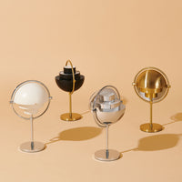 Four decorative globes in black, gold, silver, and white on a warm beige background. Elegant designs and modern finishes.