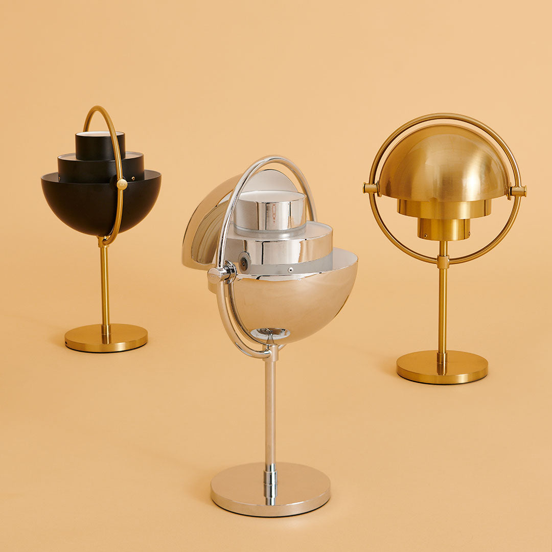 Three decorative globes in black, silver, and gold on a soft peach background. Modern design with sleek finishes.