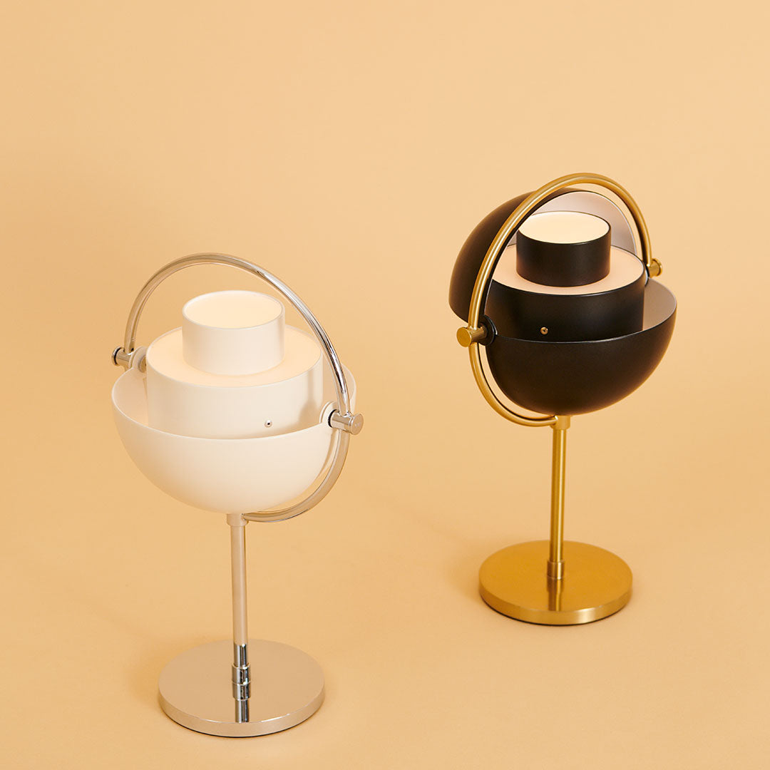 Two modern lamps in white and black with silver and gold accents against a soft beige background.