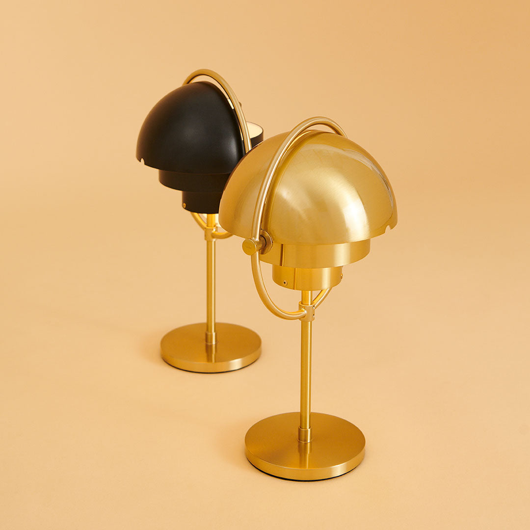 Black and gold table lamps with sleek, modern design on a soft orange background.