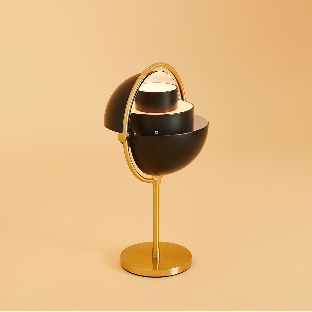 Black and gold table lamp with a modern design and circular patterns against a soft beige background.