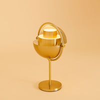 Gold modern lamp with a sleek, rounded design and a minimalistic pattern against a soft, warm orange background.