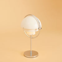 White dome lamp with a silver stand against a soft beige background, showcasing a modern design.