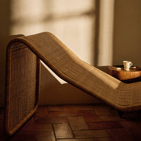 Natural woven lounge chair in warm beige tones with a textured pattern, complemented by soft shadows and light.