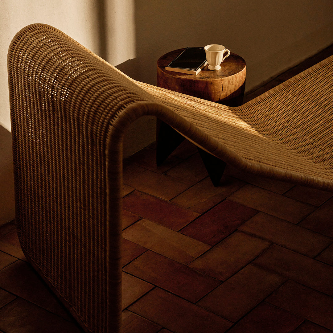 Natural woven fabric in warm beige tones, featuring a sleek, curved design on a rustic tiled floor.