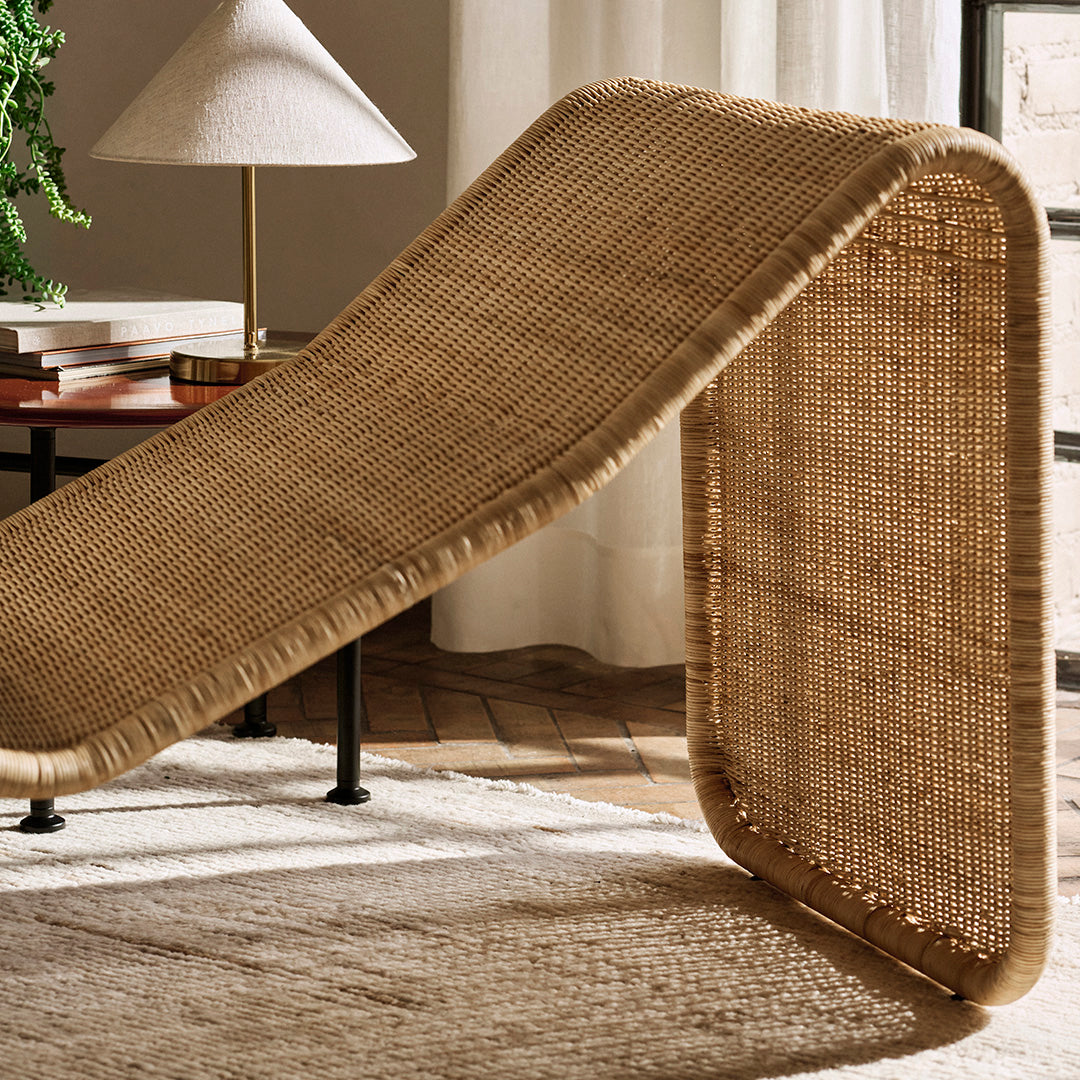 Natural woven rattan lounger in warm beige tones with a textured, curved design for modern decor.