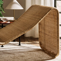 Natural woven rattan lounger in warm beige tones with a textured, curved design for modern decor.