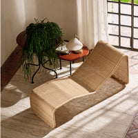 Natural woven rattan chaise lounge in light beige, showcasing a sleek, modern design with soft curves.