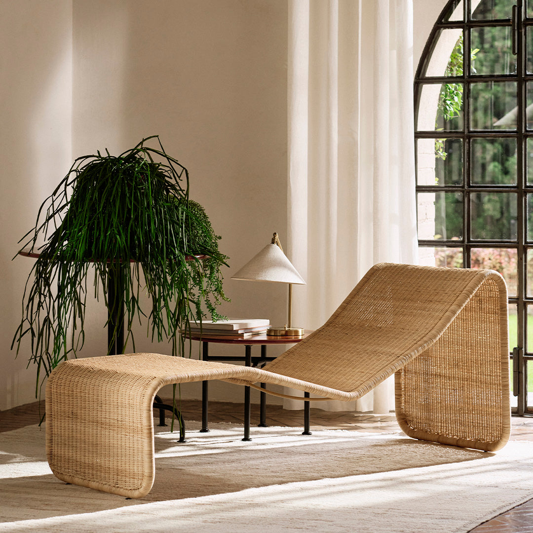Natural wicker lounge chair with a smooth, curved design, showcasing warm beige tones against a bright, airy backdrop.