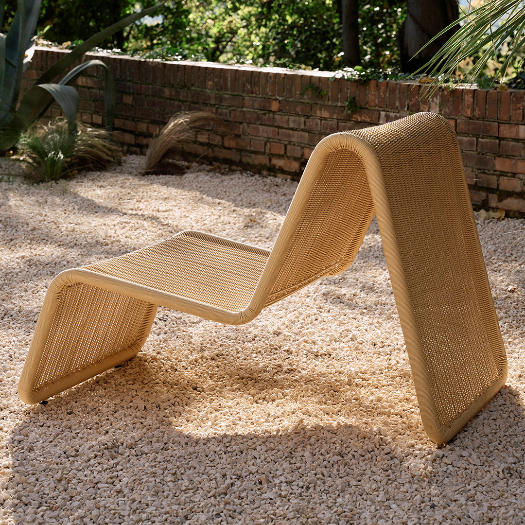 Modern curved lounge chair in natural beige with textured woven pattern, perfect for outdoor settings.