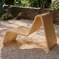Modern curved lounge chair in natural beige with textured woven pattern, perfect for outdoor settings.