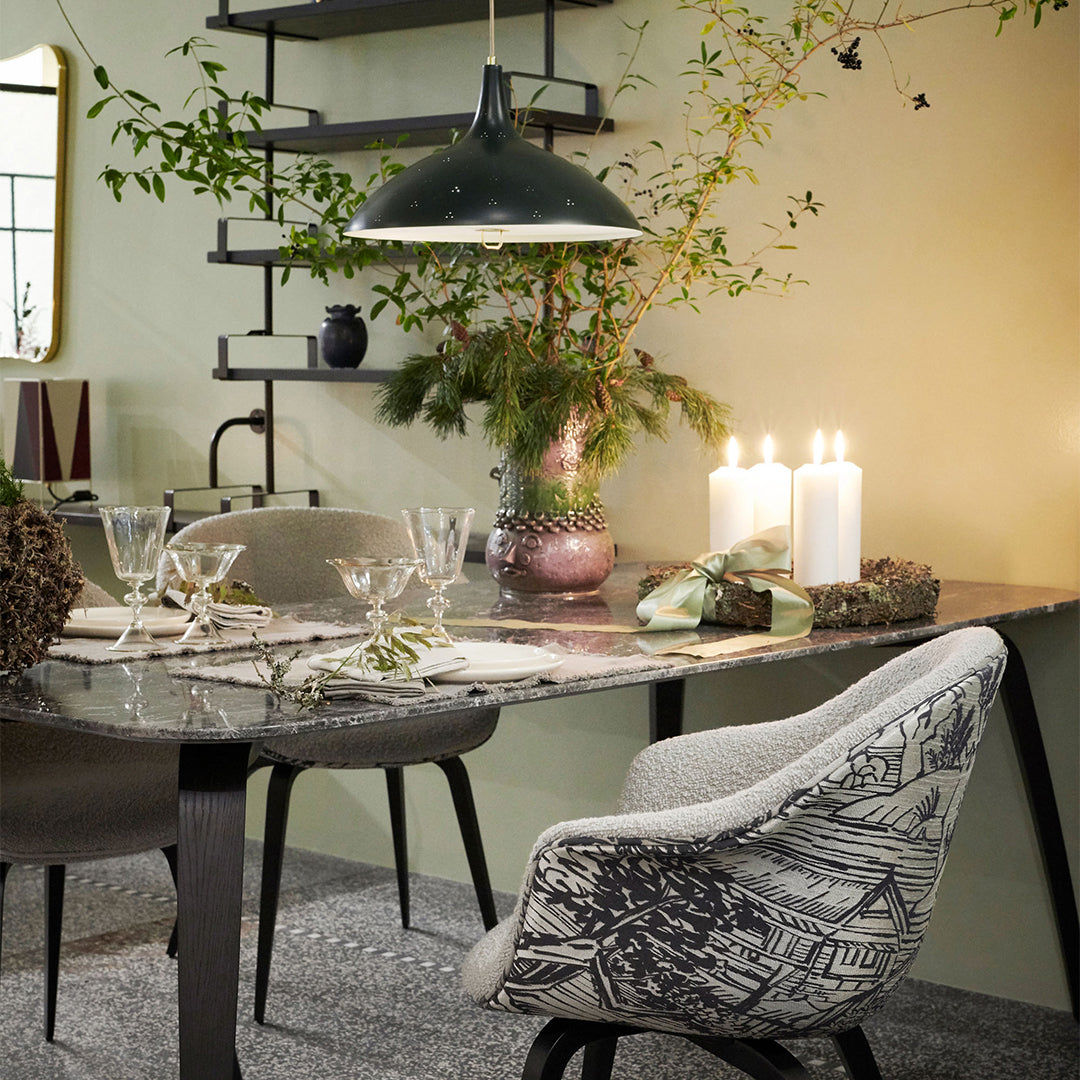 Modern dining set with gray marble table, black and white patterned chair, green accents, and soft candlelight glow.
