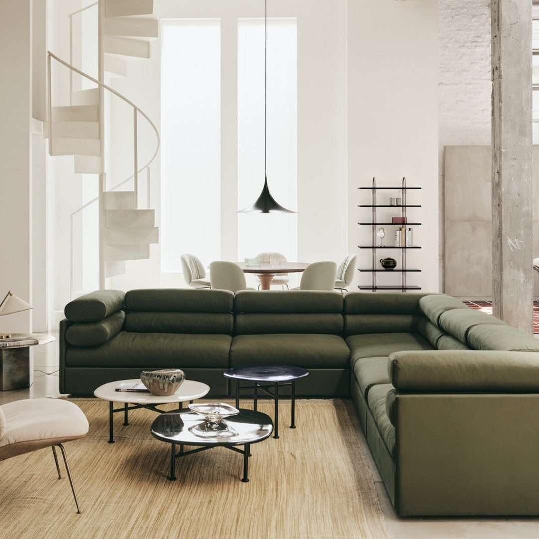 Olive green sectional sofa with sleek lines, paired with modern round coffee tables and neutral-toned decor.
