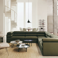 Olive green sectional sofa with sleek lines, paired with modern round coffee tables and neutral-toned decor.