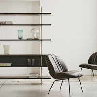 Stylish brown chair with smooth leather texture against a minimalist black shelf and neutral-toned decor.