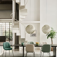 "Modern dining area with mint green and soft peach chairs, white spiral lamps, and neutral wall tones."