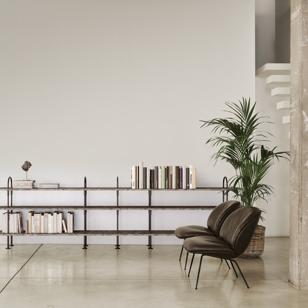 Brown leather chair in minimalist setting with neutral tones and soft green accents from the plant and books.