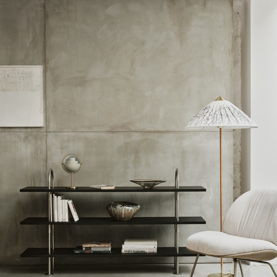 Black shelves with metallic accents, a white lamp with black patterns, and a neutral-toned background.