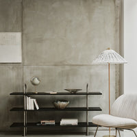 Black shelves with metallic accents, a white lamp with black patterns, and a neutral-toned background.