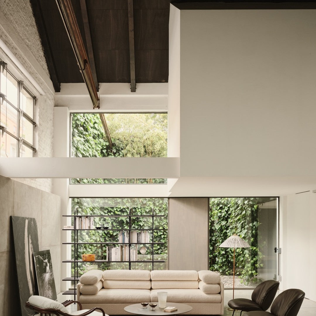 Modern interior featuring neutral tones, soft beige sofa, dark wood accents, and lush green plants.
