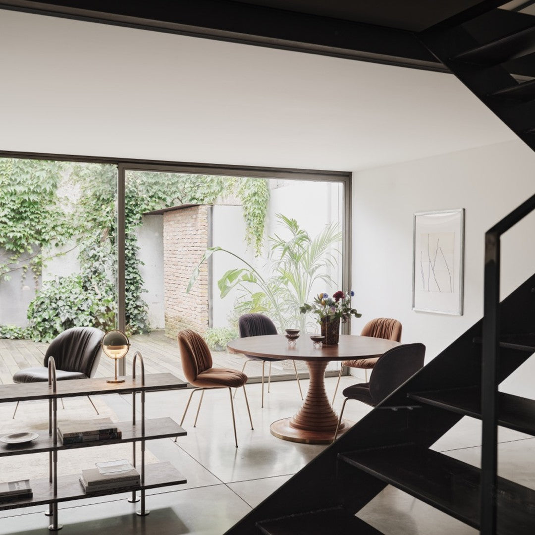 Stylish indoor dining area featuring earthy tones, rich browns, and lush greenery with modern patterns in furniture.