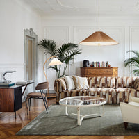 Striped beige and brown sofa with cream accents, complemented by a green rug and natural wood tones in the decor.