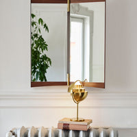 "Brass lamp with a sleek, modern design against a neutral background, featuring warm wood tones and soft reflections."