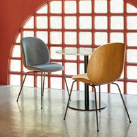 Modern chairs with blue upholstery and wooden backs, set against a red wall with a patterned glass backdrop.