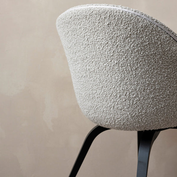 Textured light gray chair with a soft, fuzzy fabric and sleek black legs against a muted beige background.