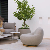 Light gray circular lounge chair with soft texture, paired with neutral-toned furniture against a minimalist backdrop.