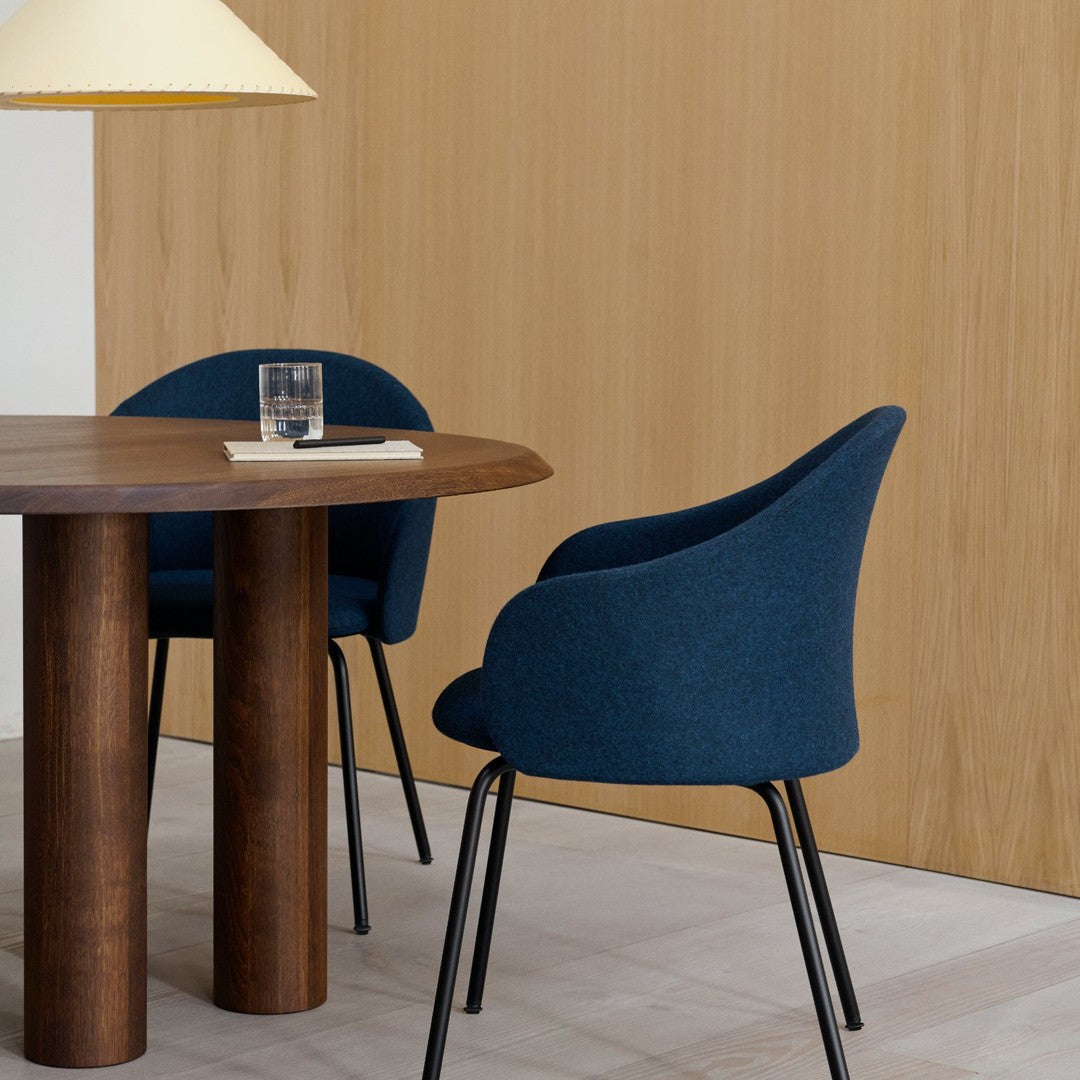 Dark blue upholstered chairs with smooth, rounded forms against a light wood backdrop. Elegant minimalist design.