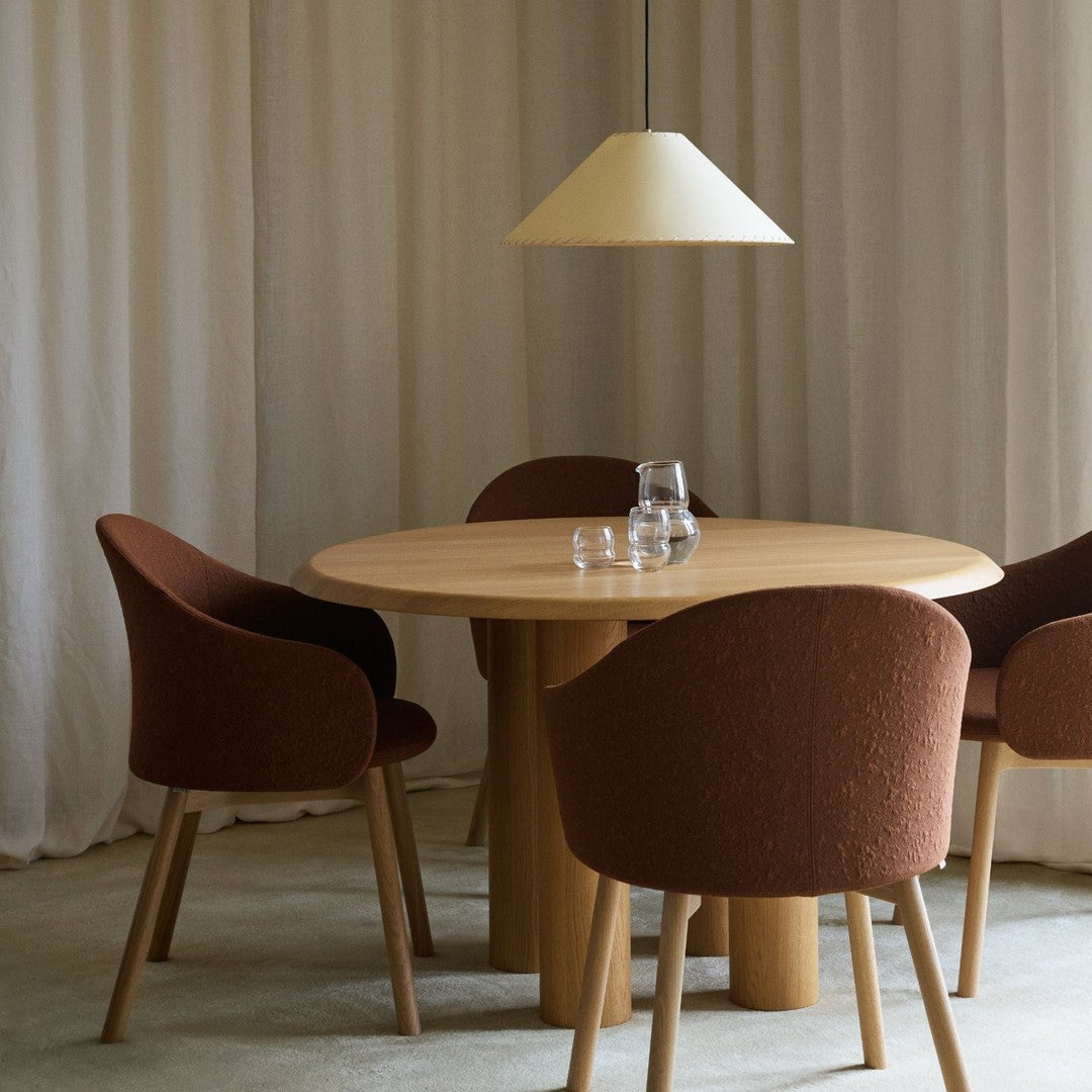 Modern dining set featuring warm brown chairs and a soft yellow lamp against neutral curtains. Elegant minimalism.