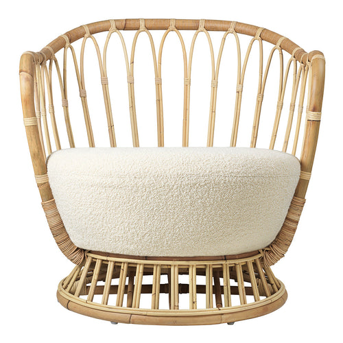 "Natural rattan chair with cream cushion, featuring a woven, open design and curved silhouette."