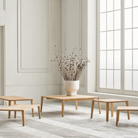 Light wood coffee tables with natural grain, set against a soft gray floor and white walls, featuring minimalistic design.
