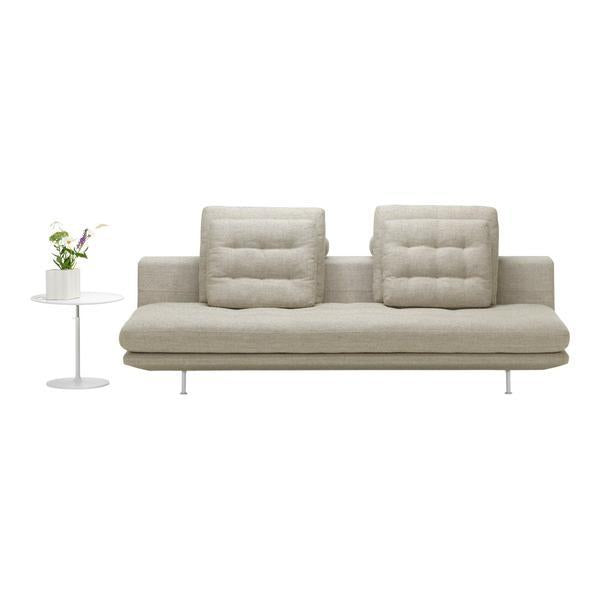 Light beige sofa with tufted cushions against a minimalistic white side table and green plant. Modern and sleek design.