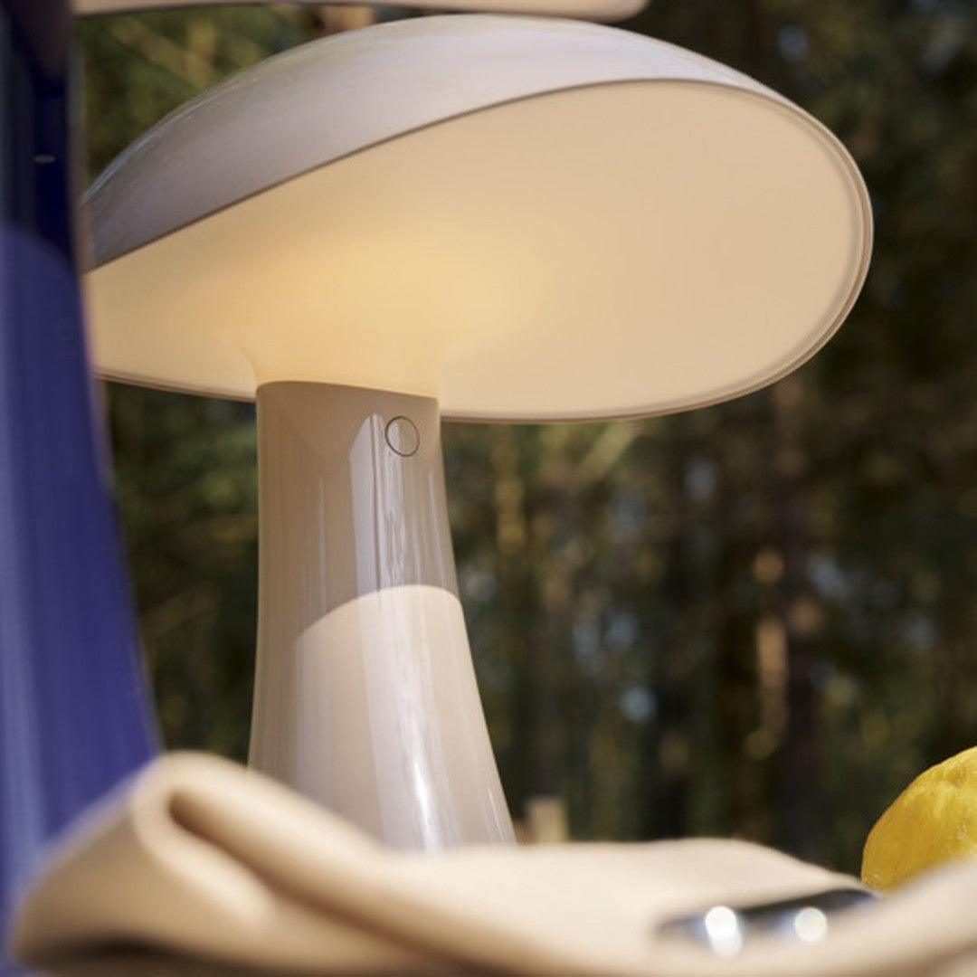White mushroom-shaped lamp with a sleek beige base, surrounded by neutral tones and natural greenery.