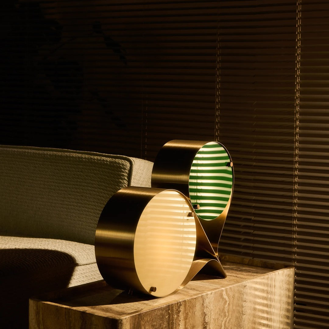 Gold and green striped lamps with a sleek design, casting soft shadows in a contemporary setting.