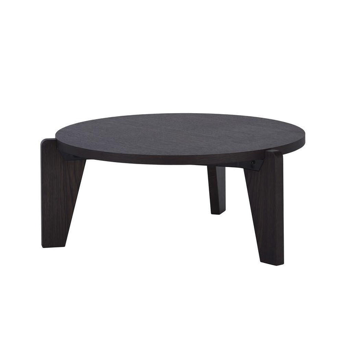 Round black coffee table with a smooth surface and minimalistic design, featuring contrasting dark wood legs.