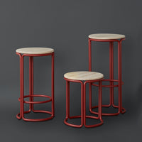 Set of three modern stools with red metal bases and round natural wood tops on a dark gray background.
