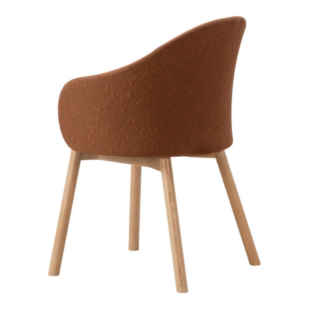 Rust-colored upholstered chair with a textured finish and natural wood legs for a warm, modern aesthetic.